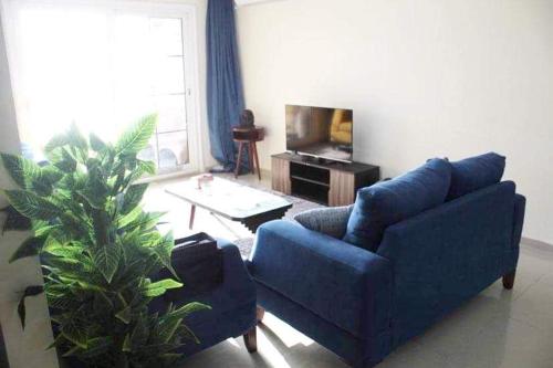sala de estar con sofá azul y TV en Breathtaking Wide Seaview Apartment, en Alejandría