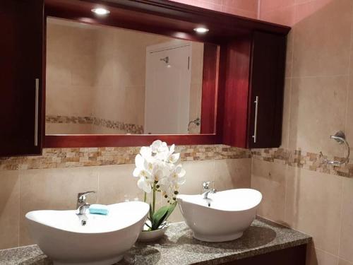 a bathroom with two sinks and a mirror and flowers at Eagle Road Holiday Home in Umtentweni