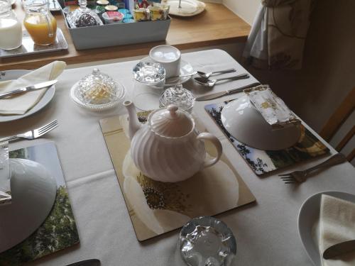 einen Tisch mit einer Teekanne, Tellern und Küchenutensilien in der Unterkunft White Cottage B and B in Spilsby