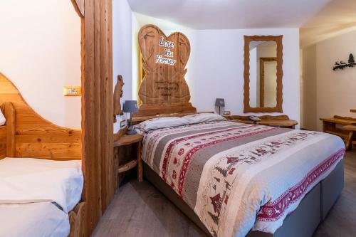 Schlafzimmer mit einem Bett mit einem Kopfteil aus Holz in der Unterkunft Hotel Arcangelo in Pellizzano