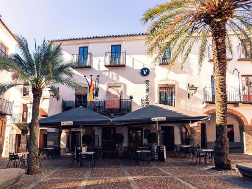 un edificio con mesas, sillas y palmeras en Hotel Las Palmeras by Vivere Stays en Zafra