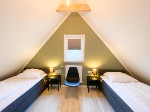 a attic bedroom with two beds and a chair at Vakantiehuis Oostkapelle OK20 in Oostkapelle