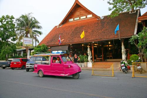 a pink car driving down a street in front of a building at Tony's Place Ayutthaya in Phra Nakhon Si Ayutthaya