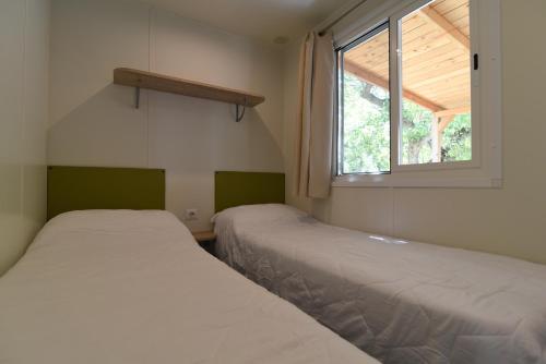 Duas camas num pequeno quarto com uma janela em International Family Camping Village Riccione em Riccione