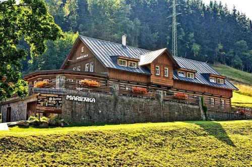 a large wooden house in the middle of a field at Penzion Marienka in Pec pod Sněžkou
