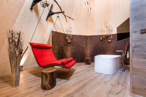 einen roten Stuhl und eine weiße Badewanne in einem Zimmer in der Unterkunft IKUNA Naturresort in Natternbach