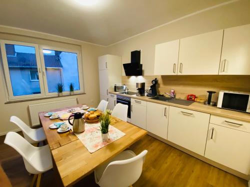 a kitchen with a wooden table and white cabinets at Gästehaus am Kurpark Hotel Garni in Horn-Bad Meinberg