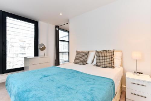 a bedroom with a large bed with a blue blanket at London Bridge Central Apartments in London