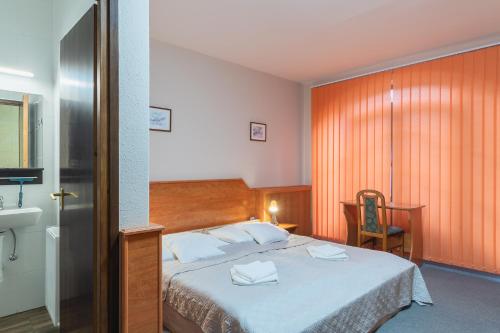 a hotel room with a bed and a chair at Delanta Panzio in Pécs