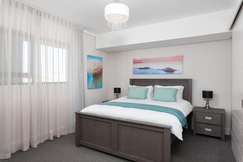 a bedroom with a large bed with blue pillows at Waters Edge Apartments in Cape Town