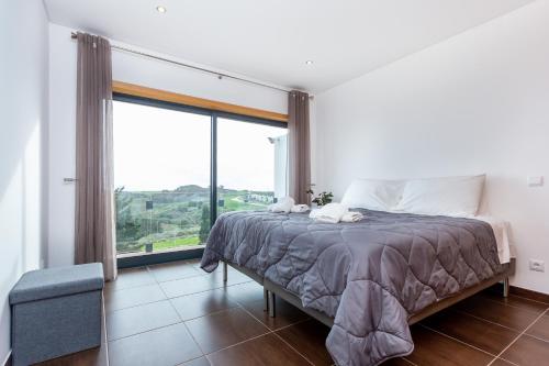 Un dormitorio con una cama y una ventana grande. en Casa Chic, en Vila do Bispo