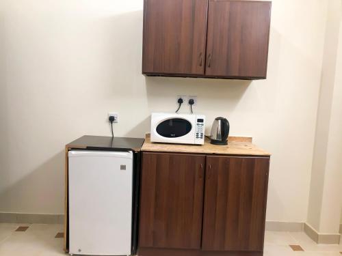 a small kitchen with a microwave and a refrigerator at رايتنا للوحدات السكنية المفروشة in Riyadh