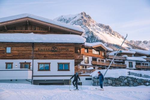 two people on skis in front of a ski lodge at Kaiserlodge in Scheffau am Wilden Kaiser