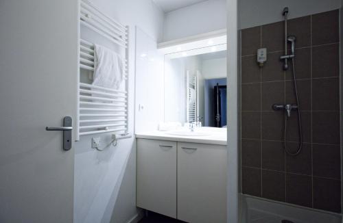 a bathroom with a shower and a sink and a mirror at Appart-Hôtel Mer & Golf City Perpignan Centre in Perpignan