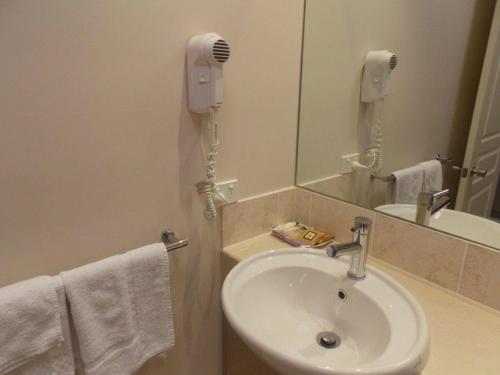 a bathroom with a sink and a phone next to a mirror at Emerald Executive Apartments in Emerald
