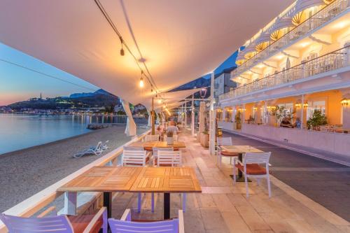 a row of tables and chairs on a building next to the water at Villa Primordia in Podgora