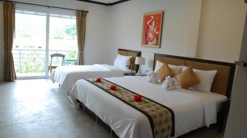 a hotel room with two beds and a balcony at Phukamala Suite in Kamala Beach