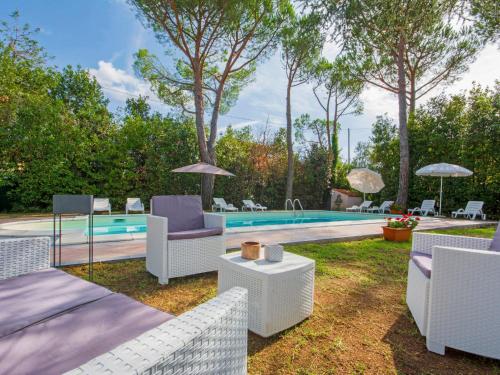 a backyard with a pool with chairs and a table at Apartment Barbara-2 by Interhome in Santa Luce