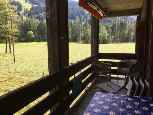 un tavolo e sedie su un portico con vista su un campo di Apartment Rothenbach by Interhome a Lenk