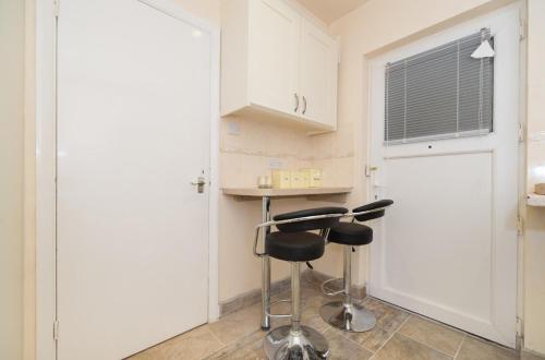 a kitchen with white cabinets and two stools at TDM Bachelot Lettings Ltd in London