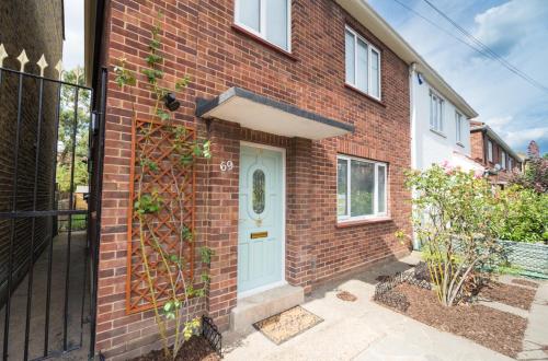 a brick house with a blue door and a gate at TDM Bachelot Lettings Ltd in London
