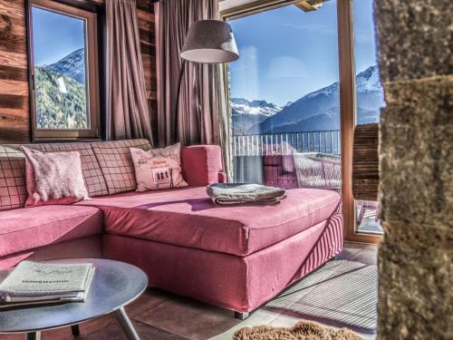 a living room with a pink couch and a large window at Holiday Home The PEAK-4 by Interhome in Sölden