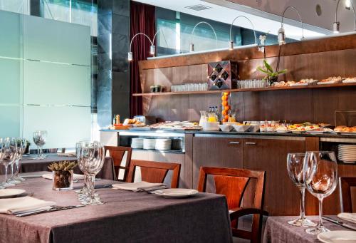 a restaurant with tables and chairs and a kitchen at Best Western Plus Hotel Alfa Aeropuerto in Barcelona