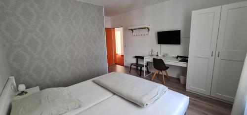 a bedroom with a white bed and a desk at City Hotel Franziska in Straubing