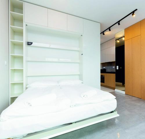 łóżko w pokoju z białymi ścianami i półkami w obiekcie Luxusowy Apartament Klimczaka w Warszawie