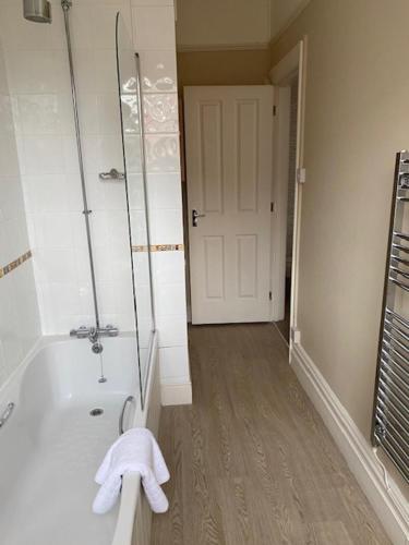 a bathroom with a tub and a shower with towels at Inn in the Park in Bournemouth
