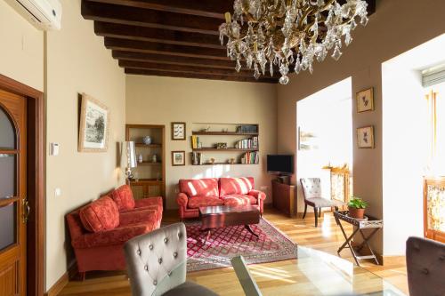 una sala de estar con muebles de color rojo y una lámpara de araña. en Veoapartment Casa Catedral, en Sevilla