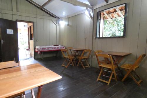 Pokój z drewnianymi stołami i krzesłami oraz oknem w obiekcie Pousada Mar Azul w mieście Trindade