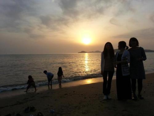 a group of people standing on the beach at sunset at Hotel Hue Loft in Incheon
