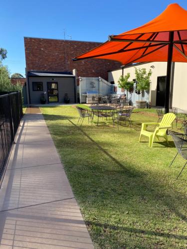 a patio with tables and chairs and an orange umbrella at Adelphi Apartment 4 in Echuca