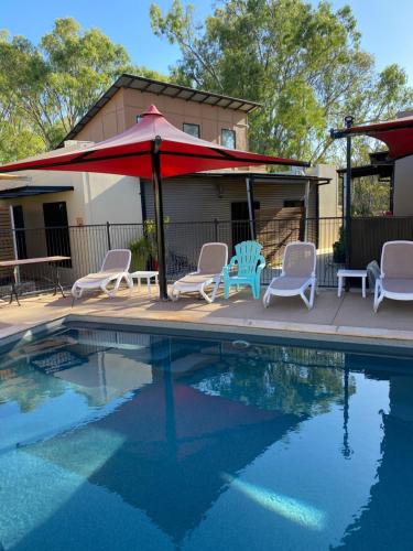 a swimming pool with chairs and a red umbrella at Adelphi Apartment 4 in Echuca