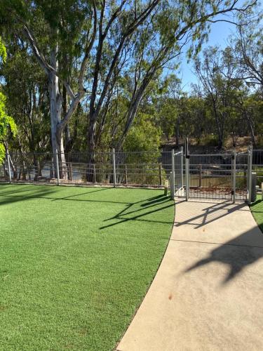 a tennis court with a fence and grass at Adelphi Apartment 4 in Echuca