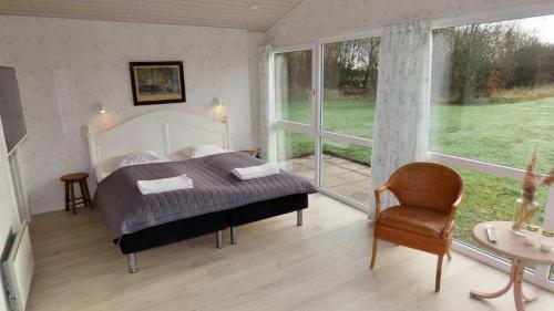 ein Schlafzimmer mit einem Bett und einem großen Fenster in der Unterkunft Axelgaard Nature Suite in Hennebjerg
