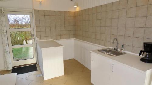 eine weiße Küche mit einem Waschbecken und einem Fenster in der Unterkunft Axelgaard Nature Suite in Hennebjerg