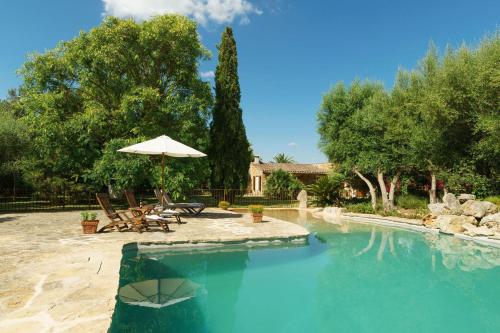 una piscina con sombrilla, sillas y mesas en Villa Amengual, en Búger