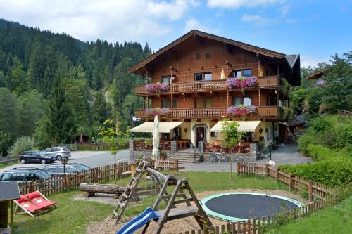 a large wooden house with a playground in front of it at Gasthof Zum Lendwirt in Westendorf