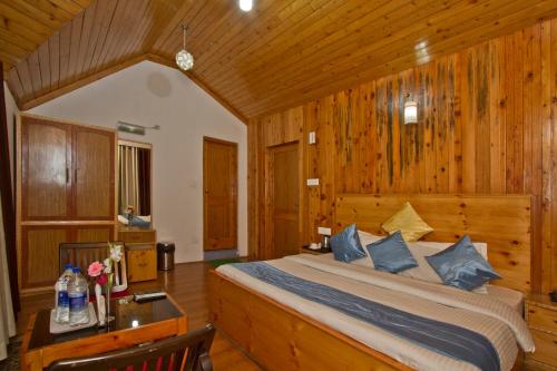 a bedroom with a bed and a wooden wall at The Cedar Cottages & Independent Villa & Kitchenette Fireplace Tandoor & BBQ in Manāli