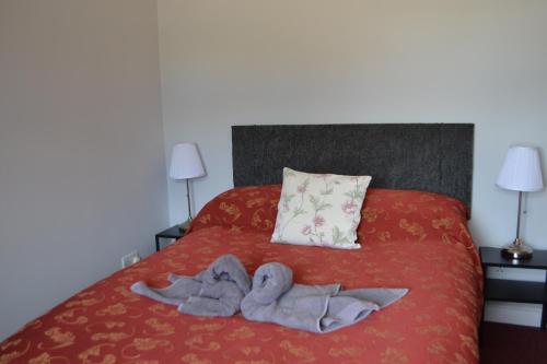 a bedroom with a red bed with towels on it at Stansted Lodge Guest House in Elsenham