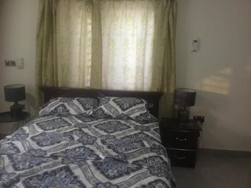 a bedroom with a bed with a quilt and two lamps at 1 Bedroom Apartment in a Prime area in Accra