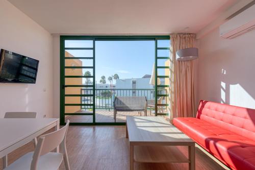 a living room with a red couch and a balcony at Apartamentos Cordial Judoca Beach in Playa del Ingles