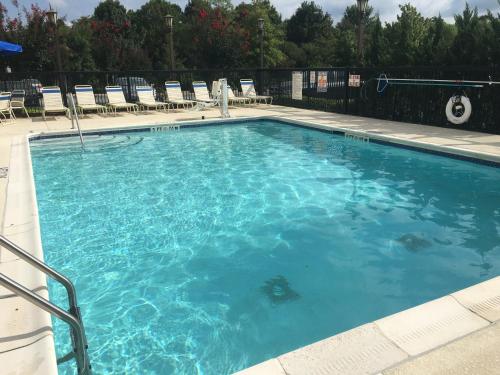 einen großen blauen Pool mit Stühlen und Tischen in der Unterkunft Holiday Inn Express Hotel & Suites Greensboro - Airport Area, an IHG Hotel in Greensboro