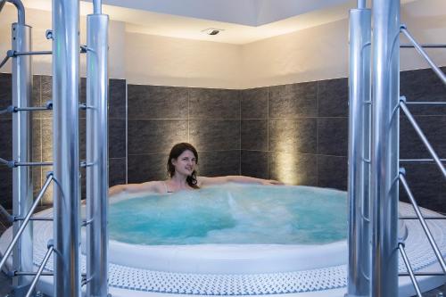 a woman in a hot tub in a bathroom at Hotel Alpen Roc in La Clusaz