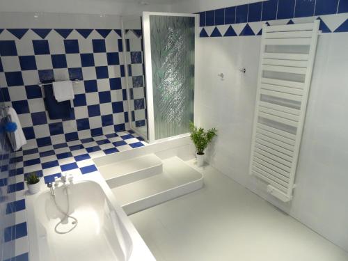 La salle de bains est pourvue d'une baignoire blanche et d'un mur en damier. dans l'établissement La Sembelie, à Carsac-Aillac