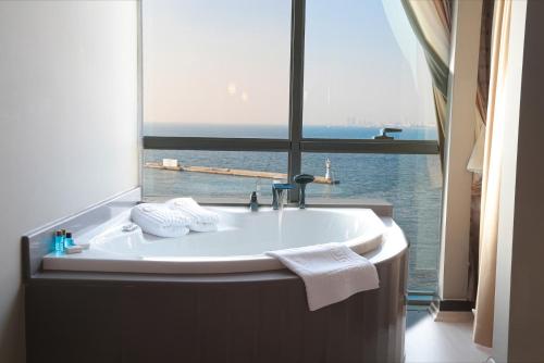 y baño con bañera y ventana grande. en Pasaport Pier Hotel en İzmir