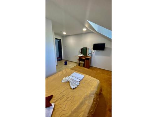ブラショヴにあるPensiunea Riccardoのベッド、デスク、テレビが備わる客室です。