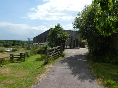 a barn with a fence next to a road at Devon Eco Lodges in Winkleigh